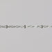 Close-up of a silver chain with beads on a light gray background