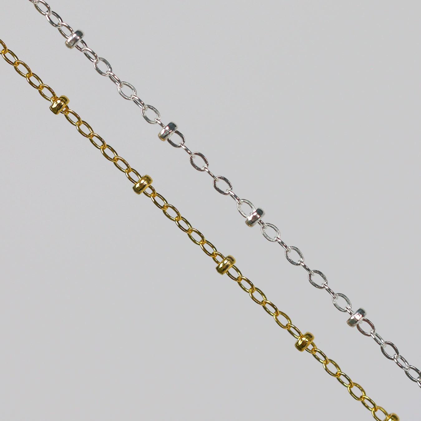 Two cable chains with beads on them. One chain is gold filled yellow and the other is sterling silver