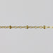 Gold chain with small cylinder beads on a light gray background