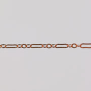 Rose gold paperclip chain on a gray background for permanent jewelry