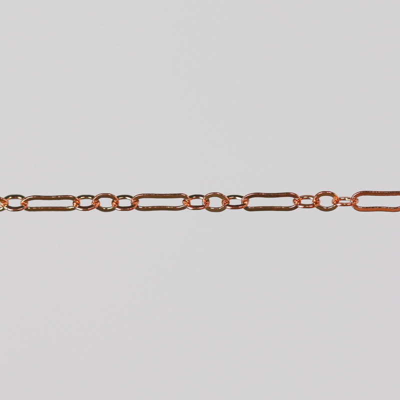 Rose gold paperclip chain on a gray background for permanent jewelry
