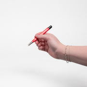 A womans hand holding a fiberglass brush while wearing two white gold permanent jewelry bracelets