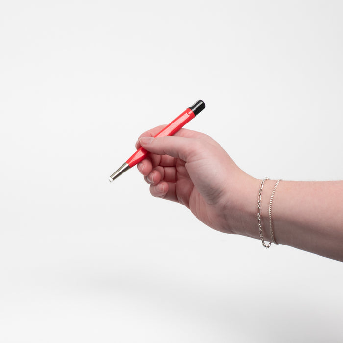 A womans hand holding a fiberglass brush while wearing two white gold permanent jewelry bracelets