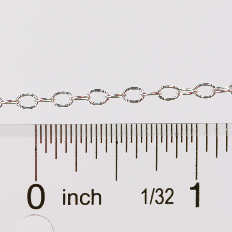 Silver chain next to a ruler on a white background