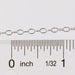 Silver chain next to a ruler on a white background