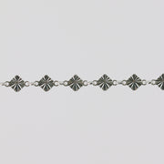 Silver bracelet with geometric star-shaped links on a light gray background