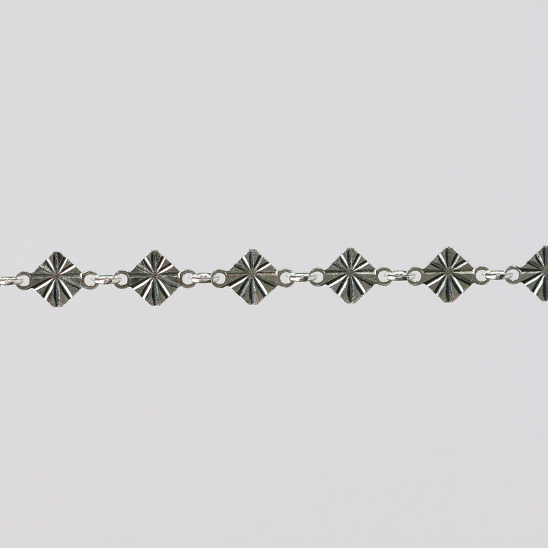 Silver bracelet with geometric star-shaped links on a light gray background