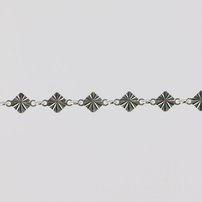 Silver bracelet with geometric star-shaped links on a light gray background