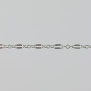 Closeup of a silver chain that has elongated links that are dapped and regular round links.
