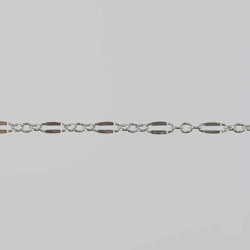 Closeup of a silver chain that has elongated links that are dapped and regular round links.