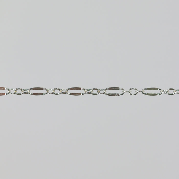 Closeup of a silver chain that has elongated links that are dapped and regular round links.