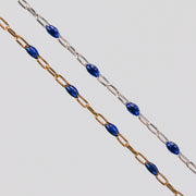 Two blue enamel permanent jewelry chains. One chain is yellow gold and the other is silver.
