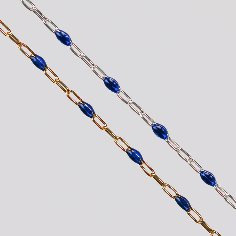 Two blue enamel permanent jewelry chains. One chain is yellow gold and the other is silver.