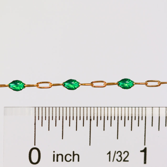 Gold chain with green enamel on it next to a ruler for measurement