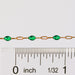 Gold chain with green enamel on it next to a ruler for measurement