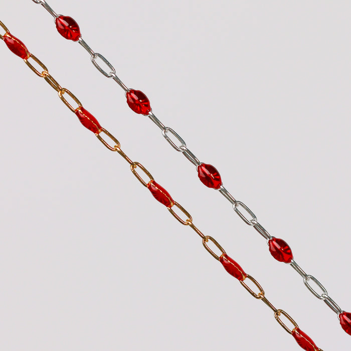 Gold and silver chains with red enamel beads on them over a gray background