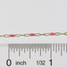Gold chain with pink enamel next to a ruler for measurement on a white background