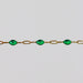 Yellow gold permanent jewelry chain with cable links and green enamel on a light gray background