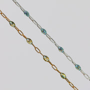 Two gold and silver chains for permanent jewelry with sparkly opal enamel on them on a light gray background