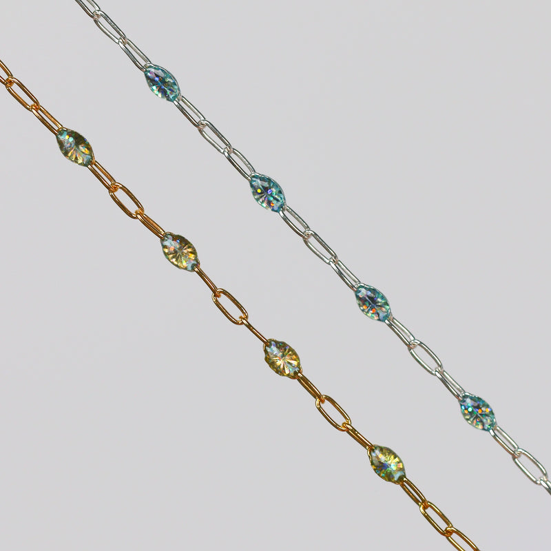 Two gold and silver chains for permanent jewelry with sparkly opal enamel on them on a light gray background