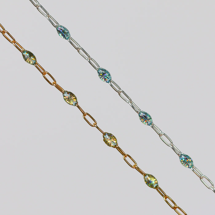 Two gold and silver chains for permanent jewelry with sparkly opal enamel on them on a light gray background