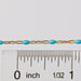 Gold chain with blue enamel beads next to a ruler for scale on a white background