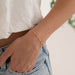 Person wearing a delicate enamel cable chain bracelet on a blurred background