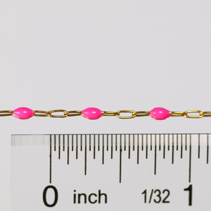 Gold chain with pink rose enamel next to a ruler for measurement on a white background