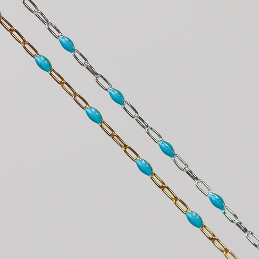 A yellow gold and a sterling silver chain with turquoise light blue enamel over a gray background