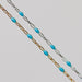 A yellow gold and a sterling silver chain with turquoise light blue enamel over a gray background