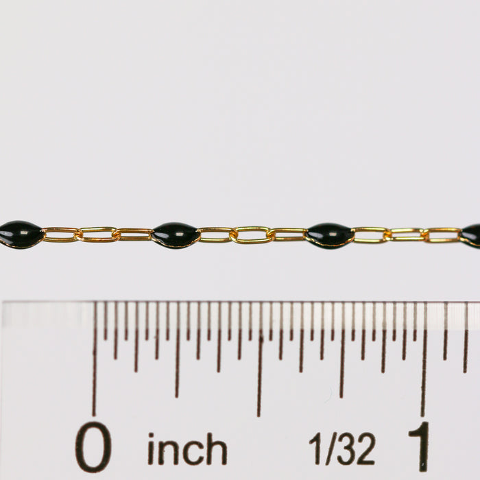Black enamel gold chain next to a ruler