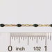 Black enamel gold chain next to a ruler