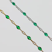 Two gold and silver chains for permanent jewelry with emerald green enamel that sparkles on a light gray background