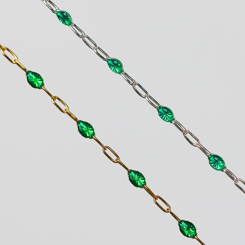 Two gold and silver chains for permanent jewelry with emerald green enamel that sparkles on a light gray background