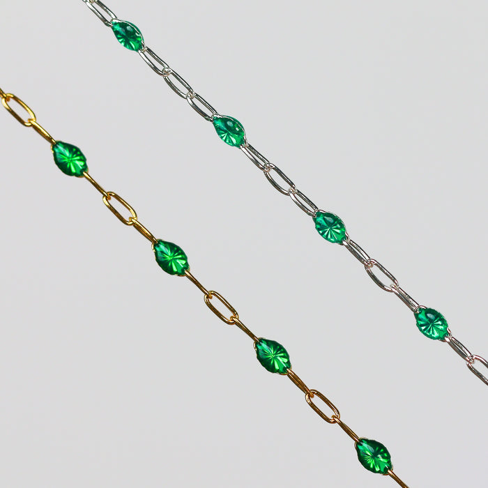 Two gold and silver chains for permanent jewelry with emerald green enamel that sparkles on a light gray background
