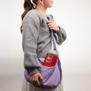 Person holding a purple bag with a small argon gas container labeled Ar on a plain background