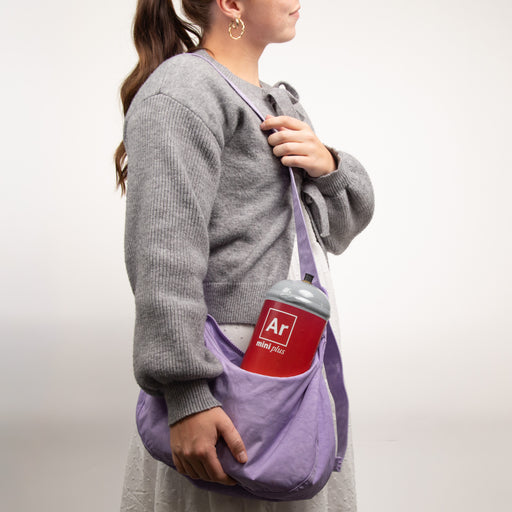 Person holding a purple bag with a small argon gas container labeled 'Ar' on a plain background