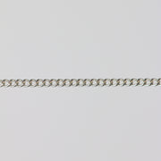 Uniform silver curb chain laying flat on a gray background