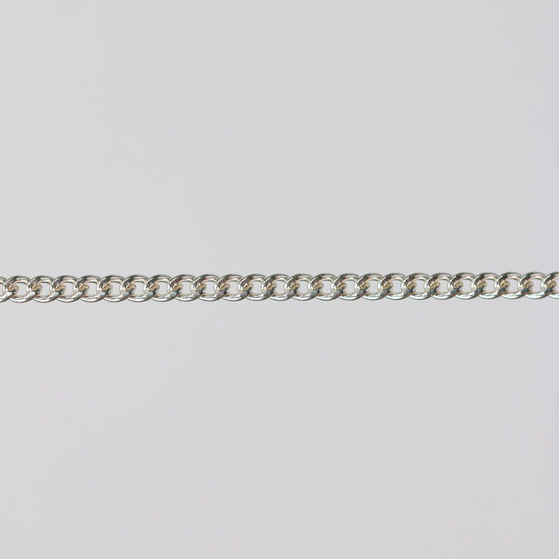 Uniform silver curb chain laying flat on a gray background