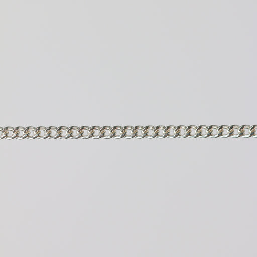 Uniform silver curb chain laying flat on a gray background