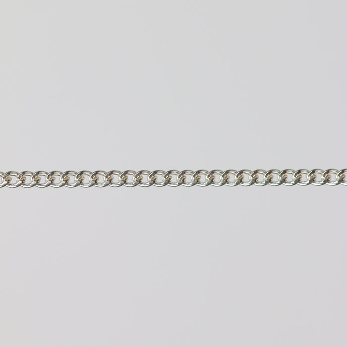 Uniform silver curb chain laying flat on a gray background