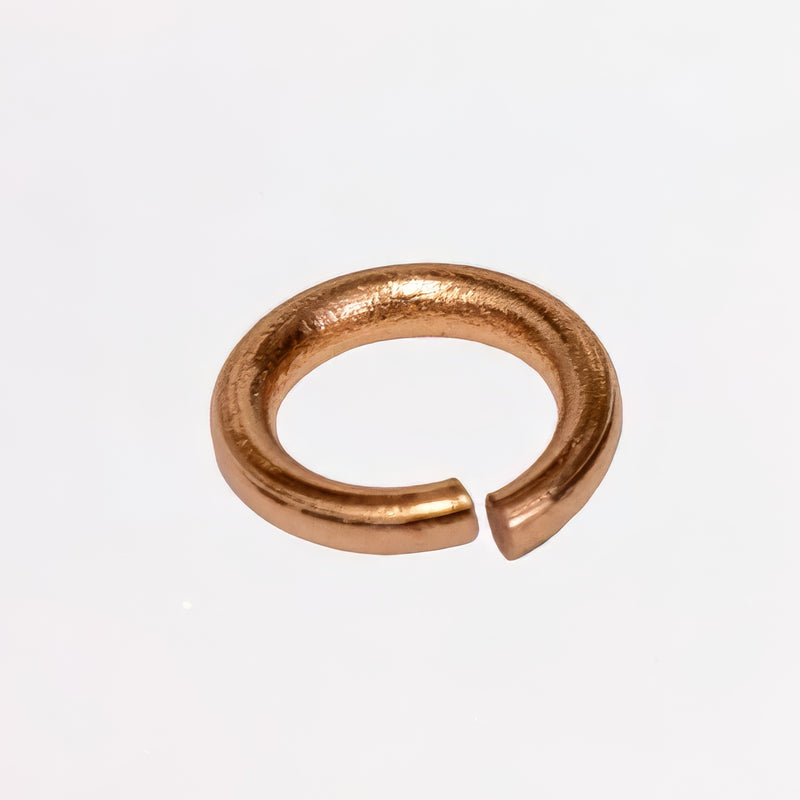 A single small open circular jump ring in 14k rose gold, photographed on a clean white background.