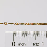 The Brittany chain in gold shown up close next to a ruler showcasing the size of the links and dapped bar design.