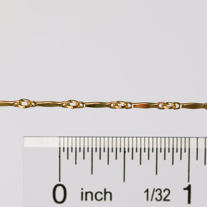 The Brittany chain in gold shown up close next to a ruler showcasing the size of the links and dapped bar design.