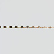 Gold bracelet with hammered squares on the links over a light gray background