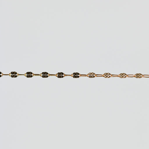 Gold bracelet with hammered squares on the links over a light gray background