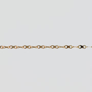 Gold chain with concave infinity symbol links on a light gray background