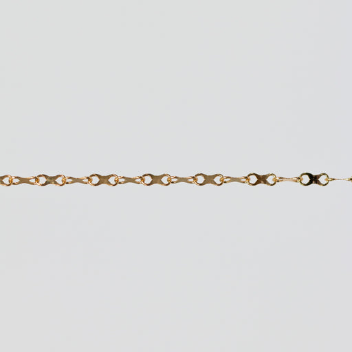 Gold chain with concave infinity symbol links on a light gray background