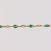 Gold chain bracelet with teal green blue enamel on it over a light gray background