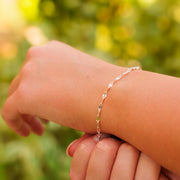 A lifestyle photo highlighting a hammered silver permanent jewelry chain worn as a delicate wrist bracelet.